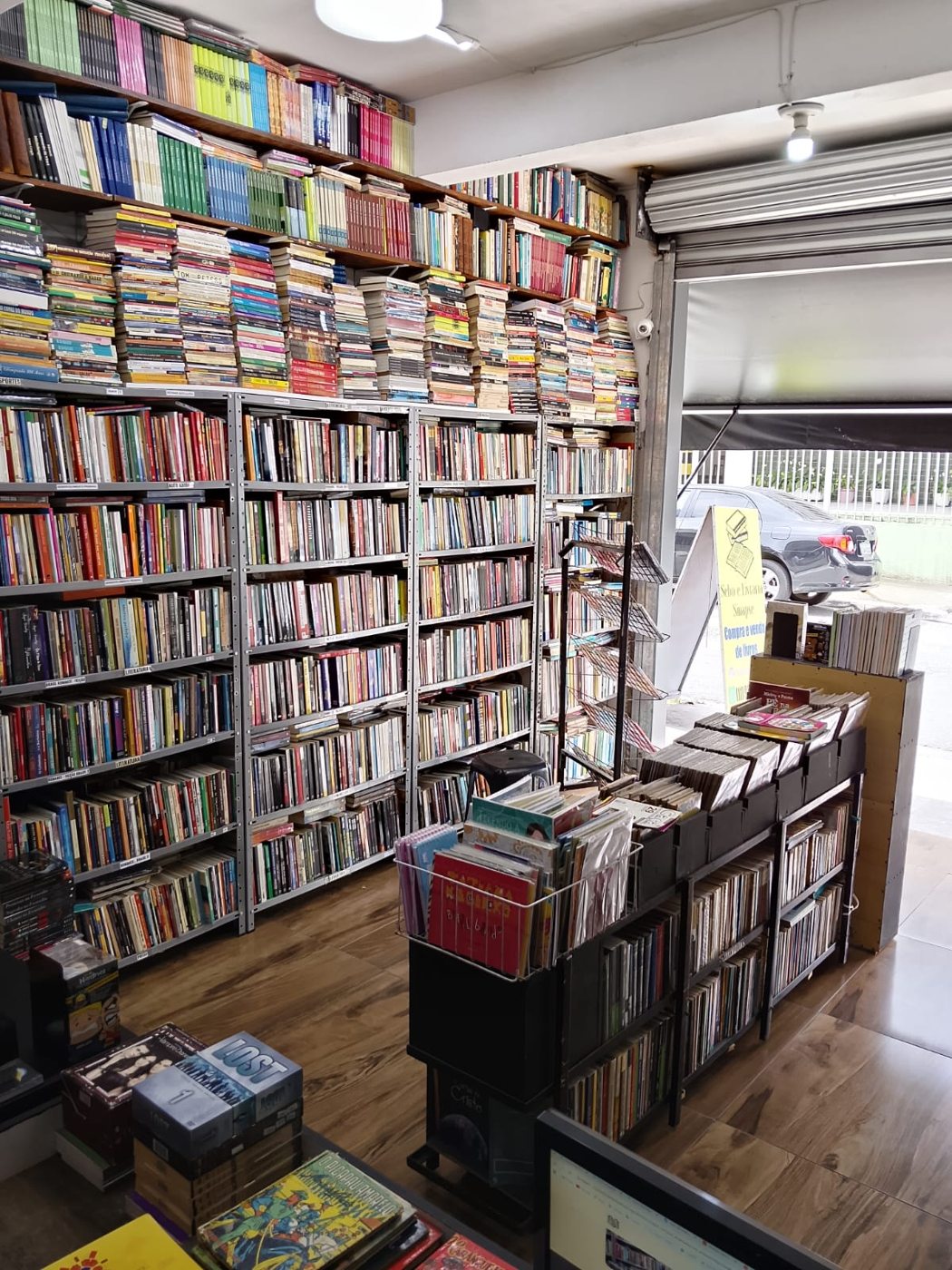 Interior da Livraria Sinapse com estantes e vista da entrada